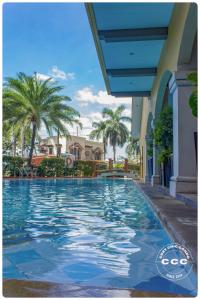 ein Swimmingpool vor einem Haus mit Palmen in der Unterkunft Cozy Chic Condotel Avida Towers Sucat in Manila