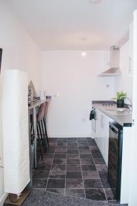 eine Küche mit weißen Wänden und Fliesenboden in der Unterkunft Modern Manor Loft in Liverpool