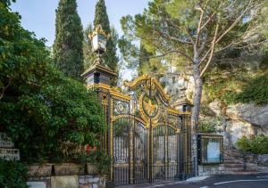 a gold gate with a clock on top of it at La Chèvre d'Or in Éze