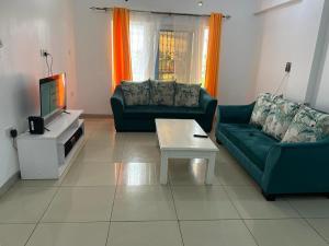 a living room with two green couches and a tv at Three Bedroom at Nyali in Mombasa