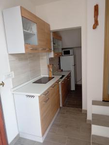 una pequeña cocina con electrodomésticos blancos y armarios de madera. en Affittacamere da Claudio&Kevin con uso cucina, en Posada