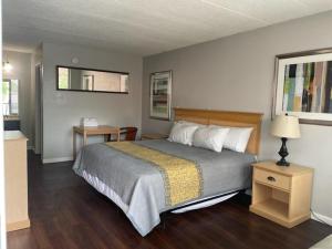 a bedroom with a bed and two tables and a lamp at APM Inn and Suites in Winchester