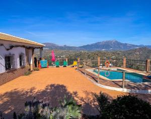 a house with a swimming pool and mountains in the background at El Mirador del Abuelo in Málaga