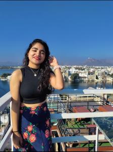 a woman standing on a balcony with a view of a city at TRIP IN HoSTEL in Udaipur