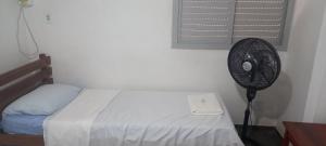 a bedroom with a fan next to a bed at Pousada Elefantinho in São Pedro da Aldeia