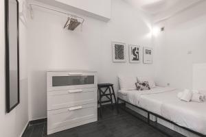 a white bedroom with two beds and a dresser at Charming Studio next to Kallimarmaro Stadium in Athens
