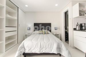 a white bedroom with a large bed and white cabinets at Modern Studio Apartment In Los Laureles in Asunción
