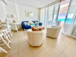 uma sala de estar com um sofá azul e cadeiras brancas em 703 Marbella 2bedroom Beachfrom Apt em San Pedro de Macorís