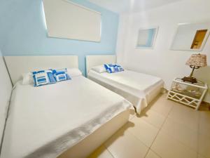 Duas camas brancas num quarto com um candeeiro em 703 Marbella 2bedroom Beachfrom Apt em San Pedro de Macorís