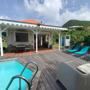 una terraza de madera con piscina y una casa en Villa Piscine - Bougainvillier, en Les Anses-dʼArlet