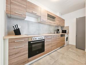 a kitchen with wooden cabinets and a stainless steel refrigerator at RAJ Living - 2 Zimmer Wohnungen mit Balkon - 25 Min zur Messe DUS in Heiligenhaus