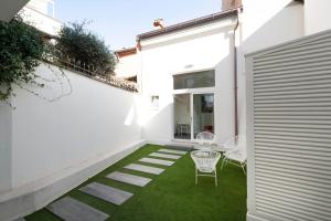 eine Terrasse mit grünem Gras und weißen Wänden und Stühlen in der Unterkunft Palazzo Ruzante Padova - Barcellona Apt in Padua