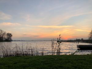 a view of a lake with a dock at sunset at Camping De Hof van Eeden in Warmond