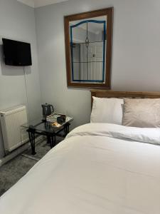 a bedroom with a bed and a table with a mirror at Windsor Wine and Dine in Chertsey