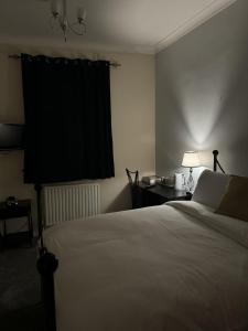 ein Schlafzimmer mit einem Bett und einem Tisch mit einer Lampe in der Unterkunft Windsor Wine and Dine in Chertsey