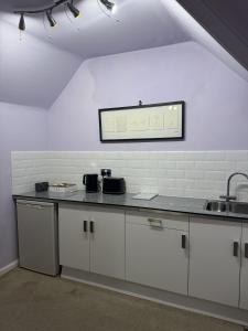 a kitchen with white cabinets and a counter top at Windsor Wine and Dine in Chertsey