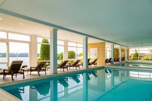 a large swimming pool with chairs and tables in a building at Seehotel Leoni in Berg am Starnberger See