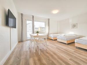 a room with two beds and a table and chairs at Tolstov Apartments - Monteurwohnungen - 2 Schlafzimmer - Küche - Balkon - Waschmaschine in Heiligenhaus