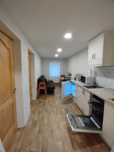 Dzīvoklis Bocmaņa laukums 2, Salacgrīva في سالاكغريفا: مطبخ بدولاب بيضاء وأرضية خشبية