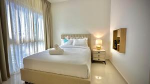 a white bedroom with a large bed and a window at Calm Chaos 4 BR Villa with maid Room in Damac Hills 2 in Dubai