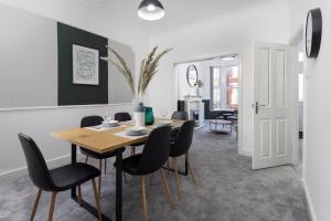 a dining room with a wooden table and black chairs at Host Liverpool - Anfield Gem, pet-friendly with garden in Liverpool