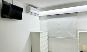 Dieses weiße Zimmer verfügt über einen TV und ein Fenster. in der Unterkunft RHASIMAR SALOU CENTRO in Salou
