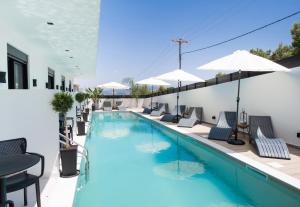 una piscina con sedie a sdraio e ombrelloni di Solvio Boutique Hotel & Spa a Città di Lefkada