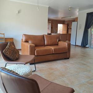 una sala de estar con un sofá de cuero marrón y sillas en Bloom en Bloemfontein