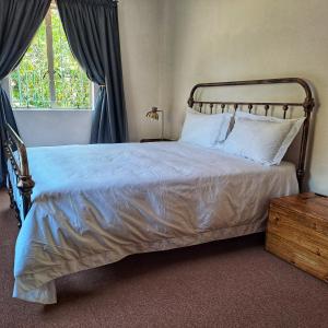 1 dormitorio con 1 cama con sábanas blancas y ventana en Bloom, en Bloemfontein