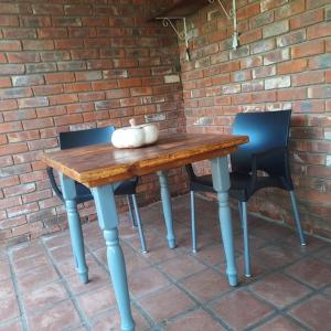 ブルームフォンテーンにあるBloomのレンガの壁の前に木製テーブルと椅子2脚