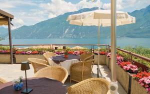 eine Terrasse mit Tischen, Stühlen und einem Sonnenschirm in der Unterkunft Hotel Ilma Lake Garda Resort in Limone sul Garda
