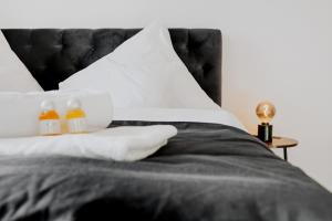 - un lit avec une tête de lit noire et 2 bouteilles d'oreillers dans l'établissement BlissPlace 3 Zi Premium Apartment nahe GETEC Arena mit Kingsize Betten und Balkon, à Magdebourg