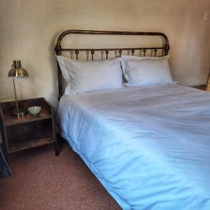 Una cama con sábanas blancas y almohadas en un dormitorio en Bloom, en Bloemfontein