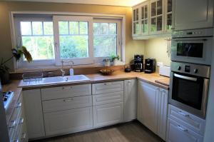 a kitchen with white cabinets and a sink at Chalet de Vasterival in Varengeville-sur-Mer +8 photos