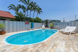 uma piscina com cadeiras e uma cerca em Pousada Costão dos Ingleses em Florianópolis