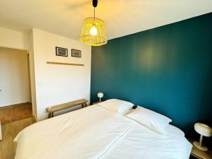 - une chambre avec un grand lit et un mur bleu dans l'établissement Bel appartement rénové dans une résidence calme, à Caen