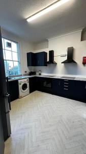 a kitchen with blue cabinets and a washing machine at 10 Minutes to Central London Vaux in London