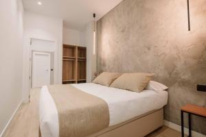 a bedroom with a white bed and a concrete wall at Rincon De La Cruz in Caravaca de la Cruz