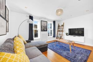 a living room with a couch and a table at Lovely 3 bedroom house in Limehouse with private parking and garden! in London