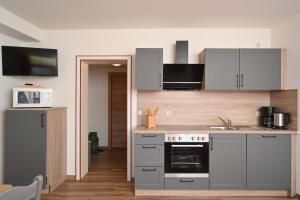 バート・ヒンデラングにあるGästehaus Landgrafの白いキャビネットとコンロ付きオーブンを備えたキッチン