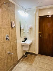 a bathroom with a sink and a wooden door at GREENS ELITE in Chennai