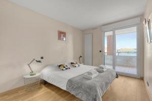 a white bedroom with a bed and a large window at Rio L'Aïga - Superbe terrasse sur Garonne in Toulouse