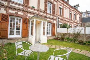 - une table et des chaises dans la cour d'un bâtiment dans l'établissement Le Puits d'Etretat-Belle maison, à Étretat