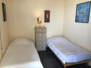 a bedroom with two beds and a dresser in it at Appart en Mer in Quiberville