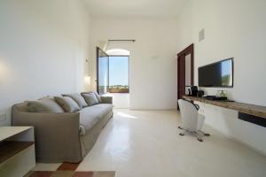 a living room with a couch and a tv at Masseria Tenute Emera By Raro Villas in Lizzano