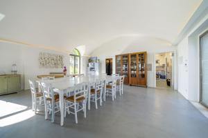 uma sala de jantar branca com uma mesa e cadeiras brancas em Masseria Tenute Emera By Raro Villas em Lizzano