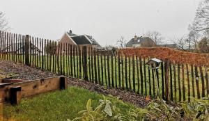 a wooden fence in a yard next to a house at Appartement YCW 'Papillon' in Rijnsaterwoude