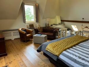 een slaapkamer met een bed, een bank en een stoel bij Plompeblad Suite Giethoorn in Giethoorn