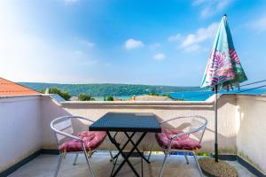 a table and chairs on a balcony with an umbrella at Apartments Antonija in Kampor