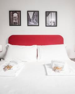 a white bed with a red headboard with pictures on the wall at Suites Campo de' Fiori - Zen Real Estate in Rome